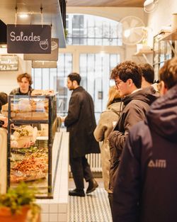 Client faisant la queue devant un comptoir réfrigéré dans un restaurant bio proposant des salades à Paris.