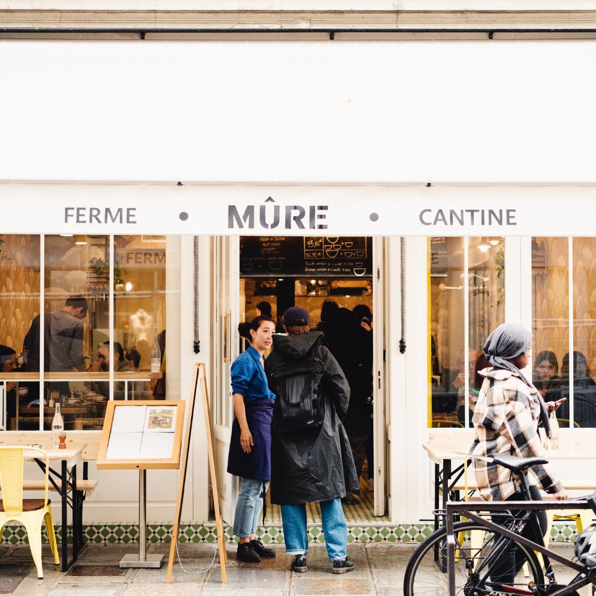 Restaurant bio MÛRE avec terrasse, décor simple et clients à l'entrée et en salle à Paris.