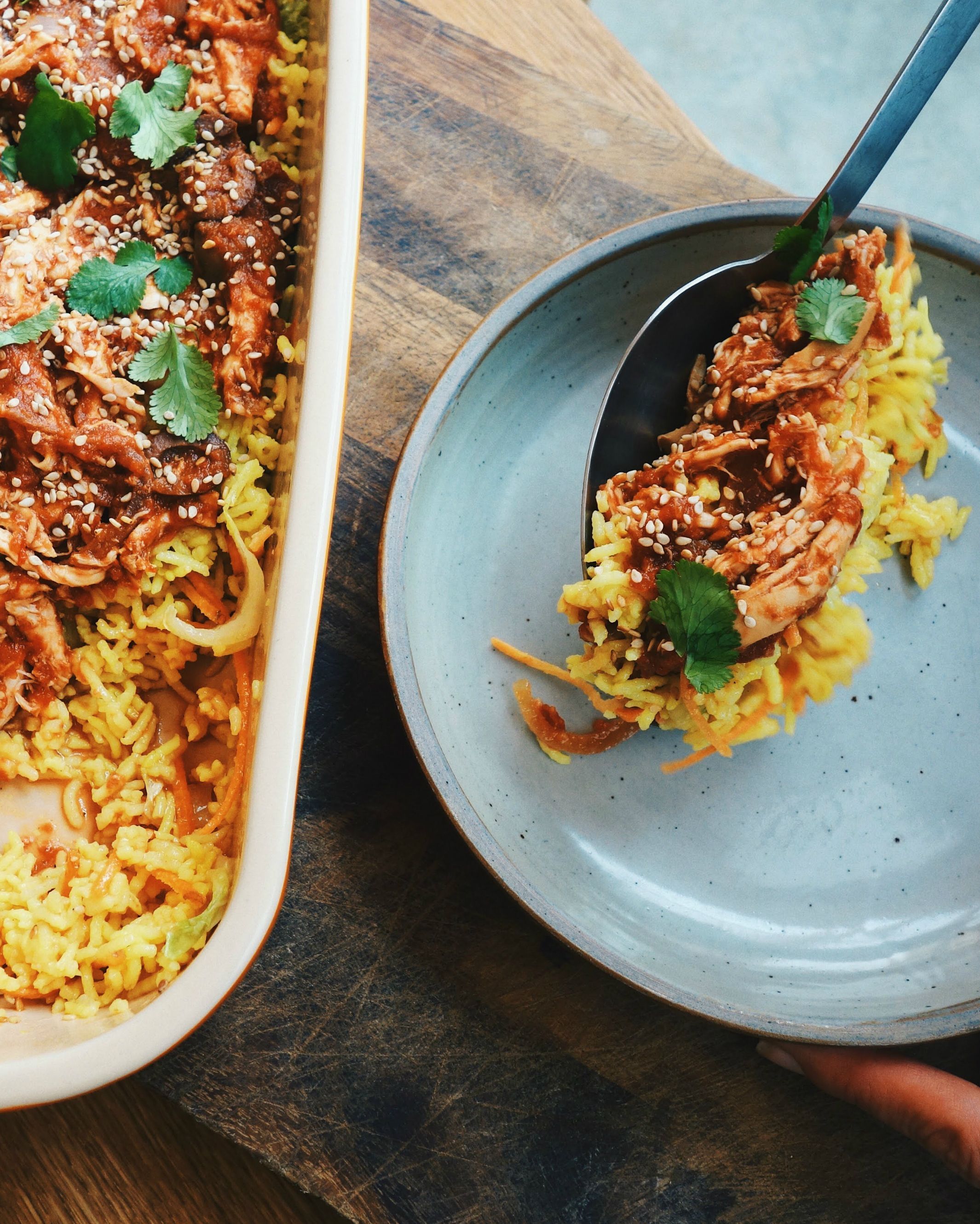 Plat de riz jaune accompagné de viande effilochée garnie de coriandre et de graines de sésame.