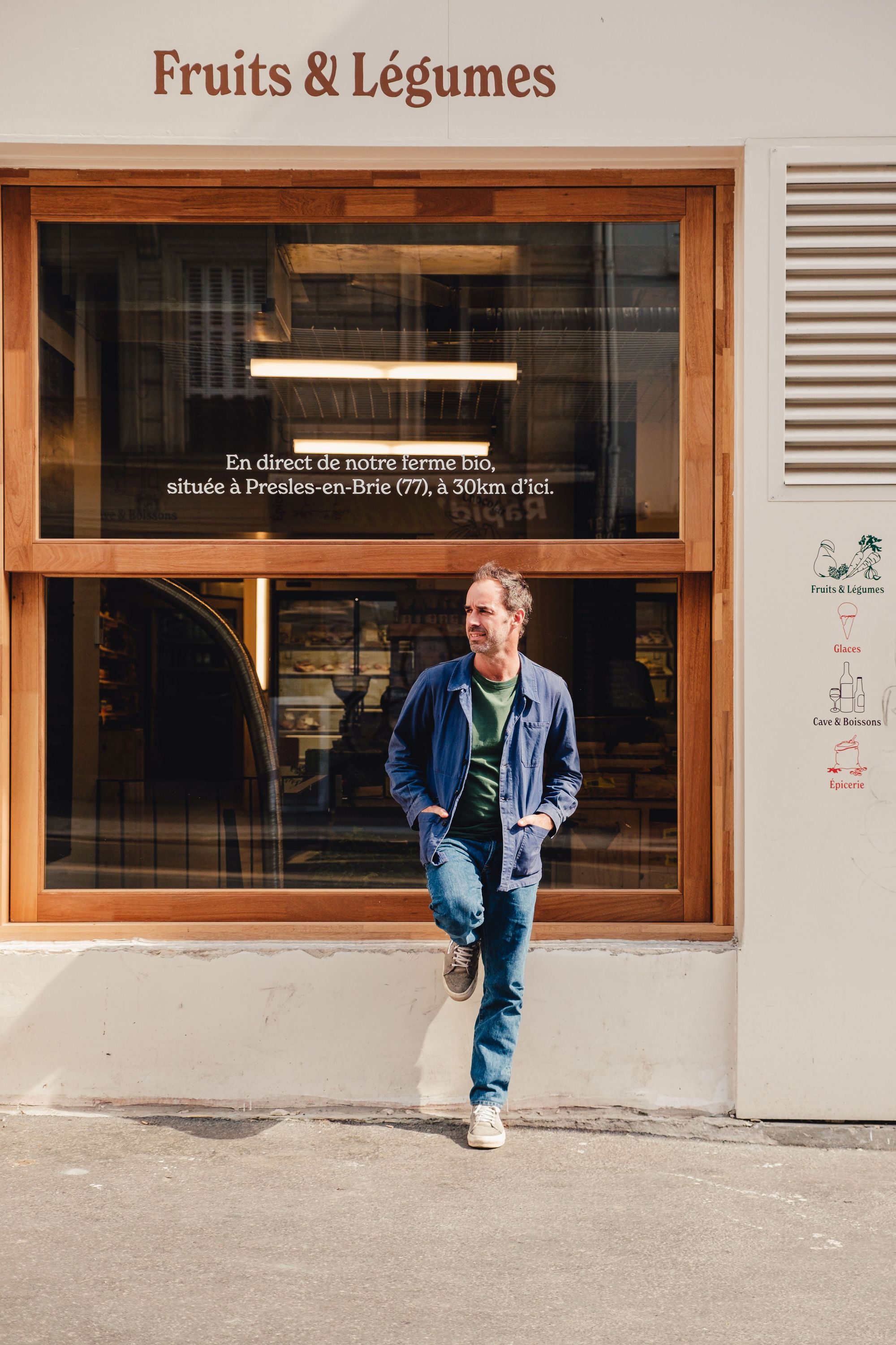 Devanture du restaurant bio MURE épicerie spécialisée en fruits et légumes à emporter, avec un homme appuyé au mur.
