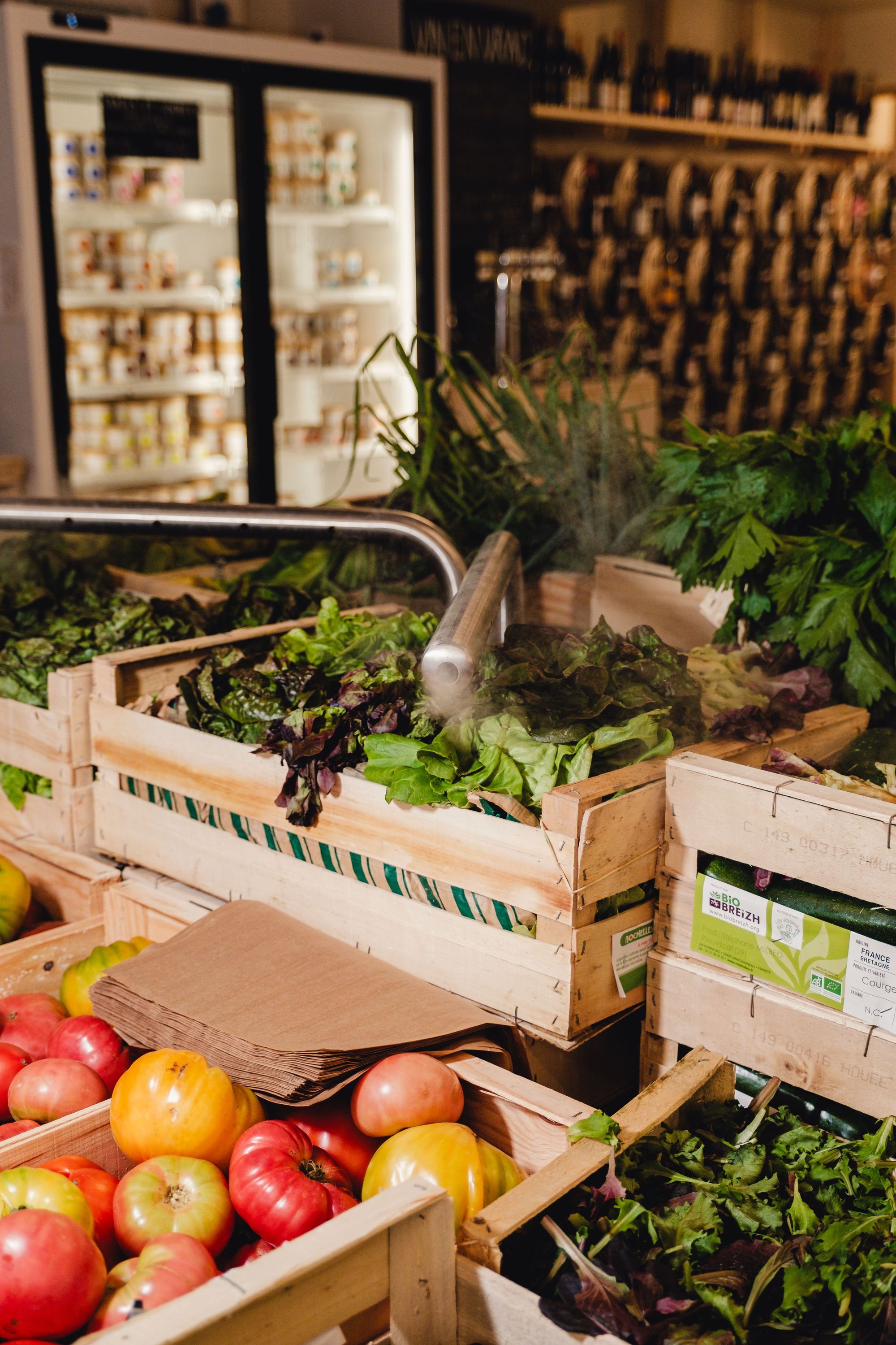 Légumes bio frais et variés comme tomates et salades dans des caisses en bois, typiques d'un restaurant bio