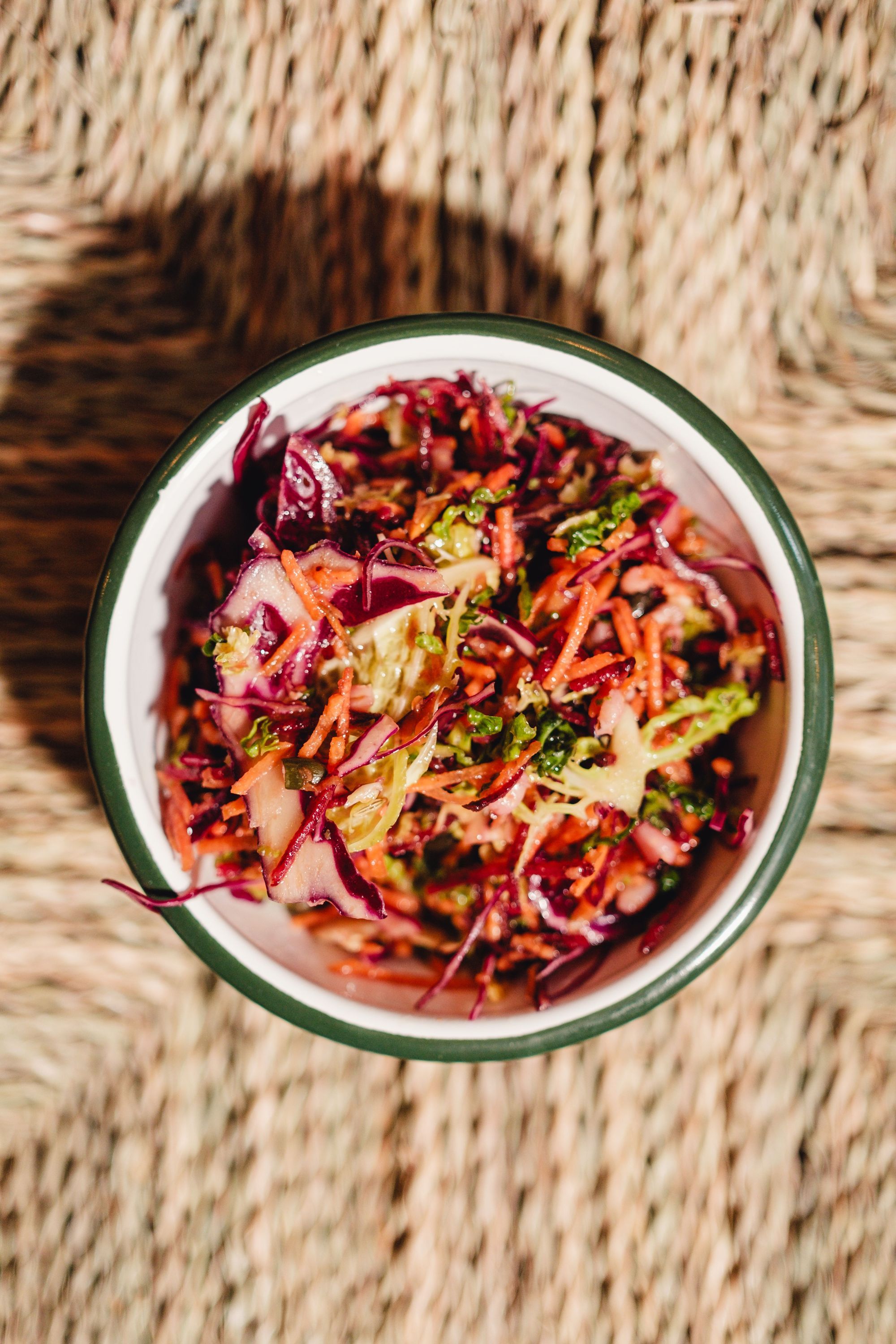 Salade colorée et végétarienne avec carottes, chou rouge et salade verte dans un bol blanc avec bord vert.