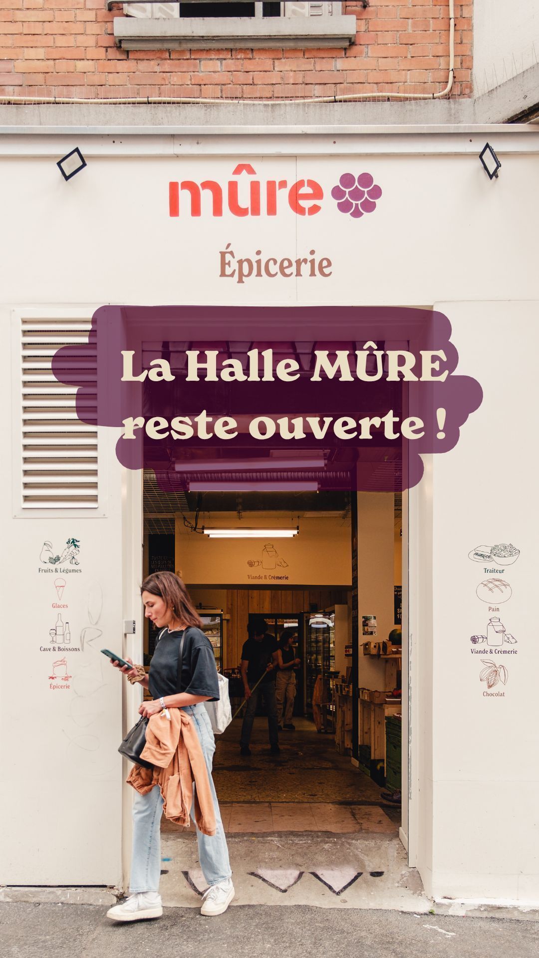 Entrance of MÛRE Épicerie with a woman standing outside looking at her phone.