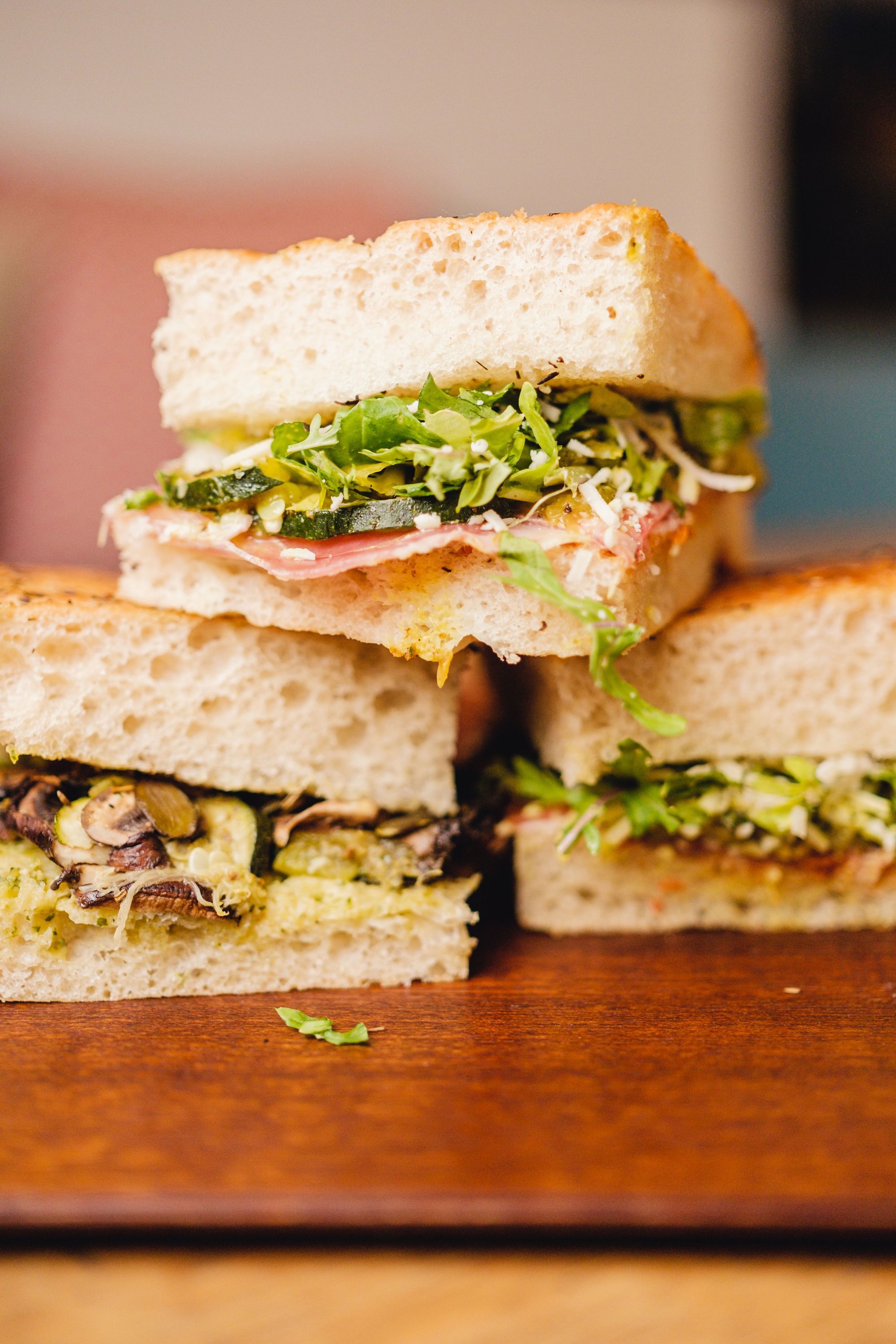 Sandwichs végétariens avec pain épais, légumes verts, champignons et assaisonnements, servis sur une planche en bois.
