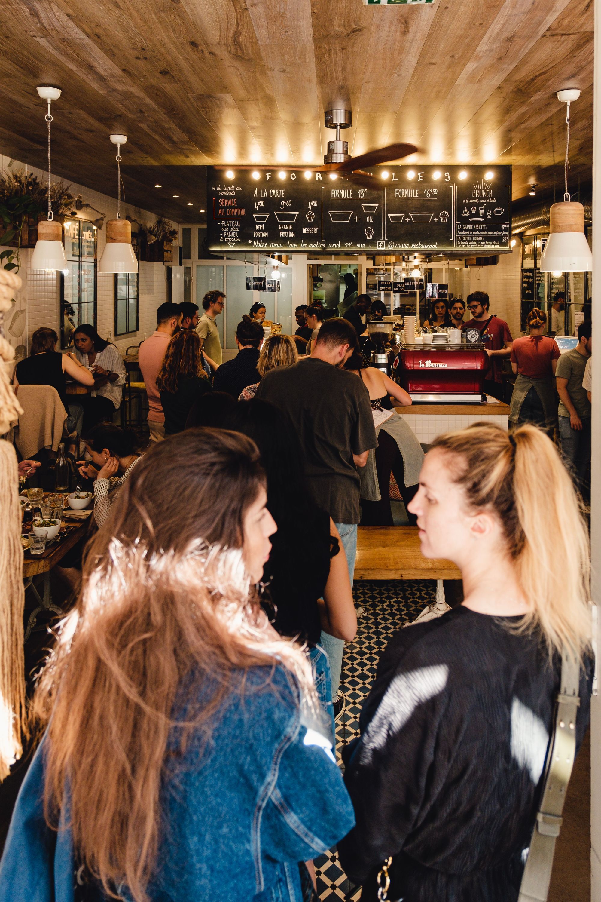 Intérieur animé du restaurant MÛRE à Paris avec clients au comptoir et menu affiché au-dessus