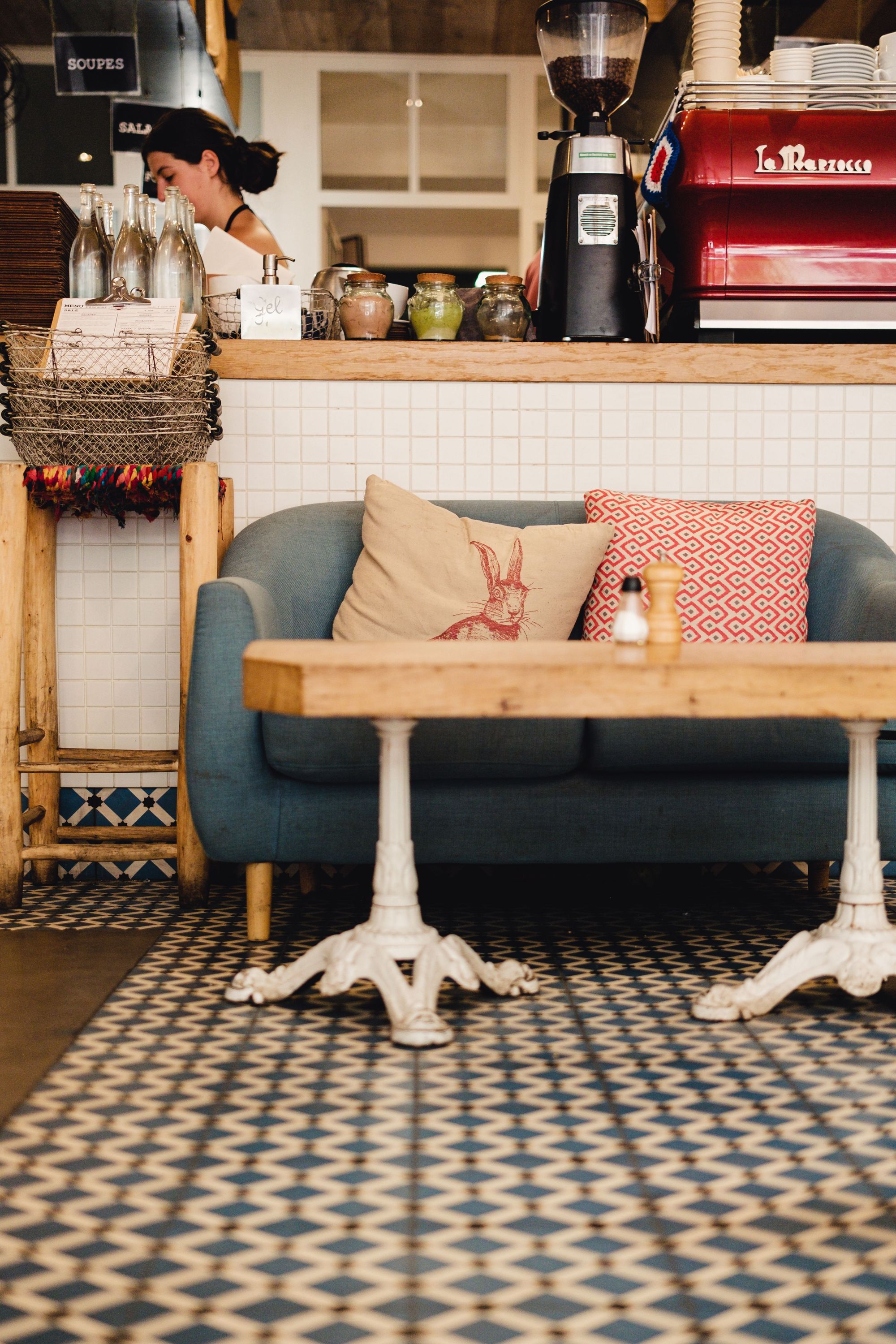 Intérieur du restaurant MÛRE avec canapé, table en bois et comptoir de boissons derrière, ambiance chaleureuse.